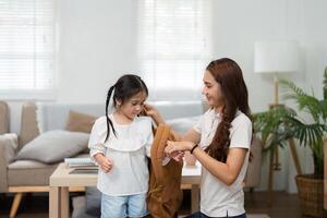 Encouraging Confidence in the School Journey. A mother helps her daughter dress while preparing for school. photo