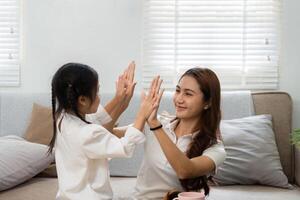 Playful Interaction and Bonding. A mother and daughter playing a hand game at home, fostering joy and connection. photo