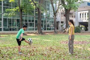 Practice and Play in Nature. A young boy practices soccer skills in a park while his mother watches with encouragement. photo