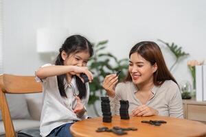 Family Bonding and Gaming. A mother and daughter play a fun domino game together, smiling and enjoying quality time. photo