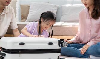 Family Bonding and Travel Preparation. A joyful interaction as a young girl explores a suitcase while her parents engage with her. photo