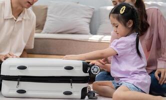 Family Fun and Interaction. A child happily exploring a suitcase with her parents nearby. photo
