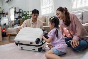 Family Bonding and Travel Preparations. A happy family excitedly engages with a child's toy suitcase, fostering bonding moments before a trip. photo