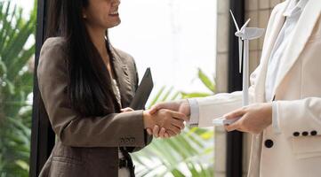 Professional Networking and ESG. Businesswomen shaking hands over sustainable practices in an office environment. photo