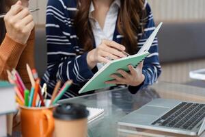Collaboration and Creativity. A student explains a concept while writing in her notebook, accompanied by a friend. photo