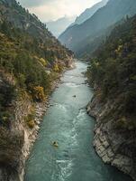 Aerial View of River Running Through Mountain Valley Featuring Green Trees and Rock Formations Under Cloudy Sky photo