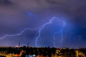 Lightning discharges in the night sky during a thunderstorm. Large thundercloud and lightning discharges. Storm. photo
