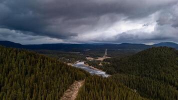 Dramatic sky over pine forest and frozen lake in mountain valley photo