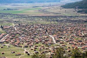 Aerial view of small village with red roofs surrounded by green fields and mountains in Bulgaria photo