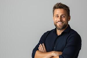 Confident young man with a friendly smile stands with arms crossed against a neutral background, conveying professionalism and approachability. photo