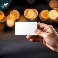 A close-up of a hand holding a blank business card with a blurred light background. Perfect for corporate identity, networking, and branding concepts. photo