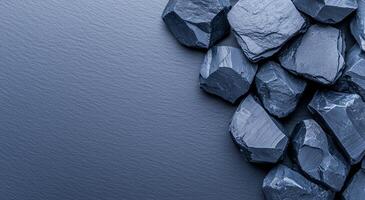 A collection of smooth, dark stones on a textured surface, creating a minimalist and calming natural composition perfect for backgrounds or design projects. photo