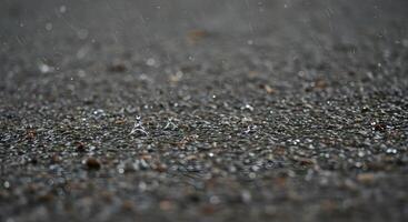 Macro view of rainwater pooling on a rugged outdoor surface with tiny ripples, ideal for nature and climate-themed projects. photo
