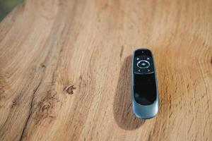 A remote control is comfortably resting on a beautifully smooth wooden table, surrounded by the rich textures of timber that significantly enhance the overall atmosphere of the entire room photo