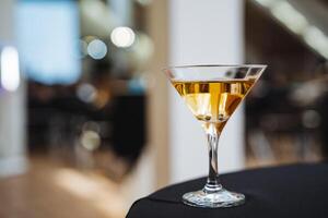 This is a meticulous closeup image of an exquisitely designed martini glass, elegantly resting on a table, highlighting its intricate details and the alluring drink contained within it photo