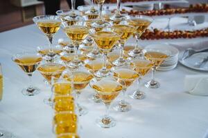 A beautiful pyramid of champagne glasses meticulously filled with sparkling champagne rests elegantly on a table, ready for guests to enjoy a delightful toast during the celebration photo
