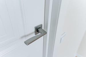 A CloseUp View of a Contemporary Modern Door Handle Installed on a White Painted Door, Set Against a Bright Interior Environment, Showcasing Its Elegance and Design Features photo