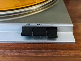 This is a detailed closeup view of a turntable placed on an elegantly crafted wooden table, showcasing the intricate design of the electronic device and its technological features photo