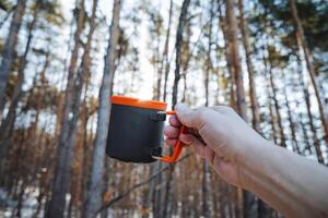 In a peaceful and serene setting, a person takes time to relax, enjoying a steaming cup of coffee surrounded by lush woods, savoring the beauty of nature with every delightful sip photo