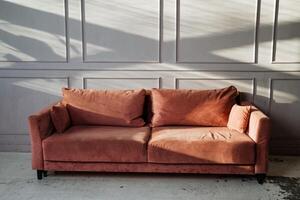 There is a lovely pink couch that is placed elegantly in front of a wall, creating a charming focal point in the room, inviting comfort and relaxation for everyone who sees it photo