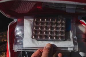 A person is holding a blister pack containing several pills in their hand, which is made of plastic and often comes in a small box that can be stored or carried as baggage photo