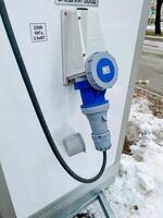 A blue plug is securely attached to a pristine white wall, indicating a connection that may involve technology or machinery, often found in various electrical applications photo