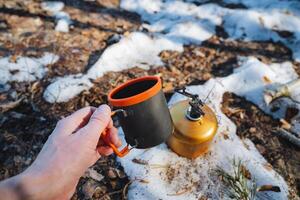 A person is joyfully holding a steaming cup of coffee while standing amidst the beautiful snowcovered landscape all around them, creating a cozy and serene scene in winter photo