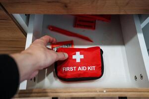 A person is meticulously and cautiously retrieving a first aid kit from a drawer, fully preparing for any potential emergency that may require swift access to essential medical supplies photo