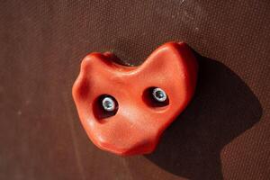A vibrant red climbing hold is securely affixed to a training wall designed specifically for indoor rock climbing enthusiasts looking for an exciting challenge and workout photo