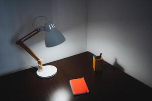A desk lamp with a notebook and pen on it photo