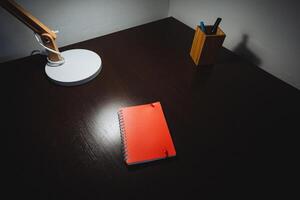 A desk with a lamp and a notebook on it photo