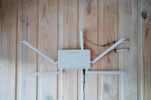 A sleek white router is prominently placed on a wooden wall, showcasing its modern design and functionality as a key electronic device for wireless internet connectivity photo