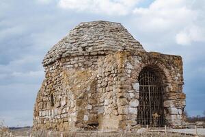 An old stone building, with its impressive structure and weathered walls, stands proudly with a cage situated in front of it, creating a unique and intriguing historical scene photo