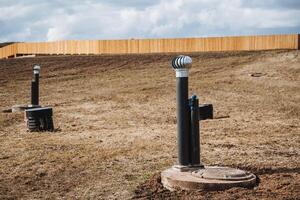 A robust and sturdy fence fully encloses a spacious field that features several scattered pipes throughout, thus creating an interesting and unique layout in this particular area photo