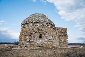 In the middle of a vast field, there stands a remarkable stone building, distinguished by a magnificent dome perched atop, drawing attention to its historic significance and beauty photo