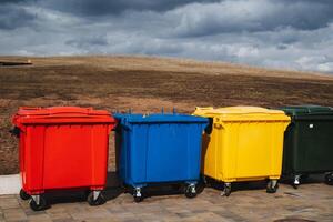 Four vibrant and colorful trash cans are neatly lined up in a row on the sidewalk, creating a visually appealing sight for pedestrians and ensuring proper waste disposal in the area photo