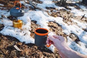 Dressed in cozy layers to combat the chill, a person enjoys a hot cup of coffee while taking in the breathtaking beauty of the winter landscape and inhaling the invigorating crisp air photo