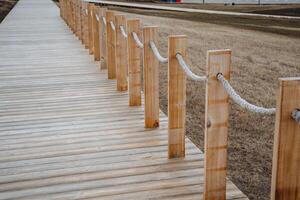 There is a wooden walkway featuring a wellconstructed rope fence situated alongside it, providing both safety and style for those walking along this beautiful path in nature photo