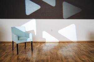 In a welldecorated room, there is a chair positioned conveniently in front of a wall that is adorned with multiple triangles painted on it, adding an artistic flair to the space photo