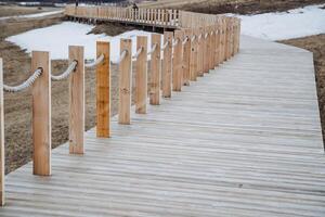 A wooden walkway that features a sturdy wooden railing and ropes for safety, providing an ideal path for pedestrians to enjoy nature and the surrounding views while walking along it photo