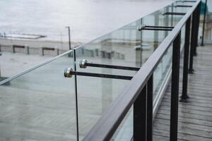 The photograph features a close up view of a sleek glass railing situated on a balcony that offers a stunning perspective overlooking the vast and beautiful ocean beyond photo