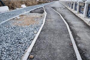 There is a road that features a distinctly marked white line running down the center, with a layer of gravel lining the sides, providing a clear demarcation for travelers photo