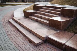 A beautiful set of stairs constructed from stone and bricks, elegantly placed on a wellmaintained sidewalk for pedestrians to use and enjoy while walking along their route photo
