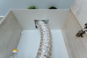 A long hose is protruding from an opening that is situated in the wall of a cabinet, and this might be associated with plumbing functions or another sort of essential utility setup photo