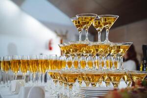 A beautifully arranged tower of champagne glasses, all filled with sparkling champagne, is elegantly displayed on a table, inviting guests to enjoy a celebratory drink together photo