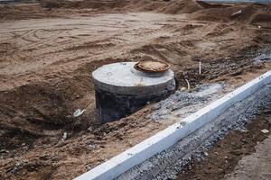 In the center of a dusty, unpaved field, a septic tank is positioned, awaiting installation and connection to the necessary plumbing systems for efficient waste management photo
