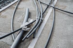 A collection of electrical wires is lying scattered across the ground in various positions and directions, creating a chaotic scene that needs careful handling and organization photo