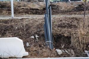 A significant number of pipes can be observed lying in the dirt beside a white barrier that separates the area, providing a visual cue of the ongoing construction activity photo