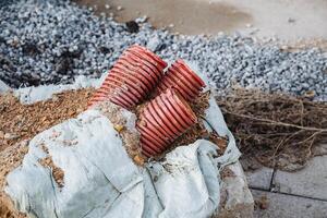 There are a couple of red pipes lying casually on top of a large pile of dirt, creating a striking contrast between the vibrant color of the pipes and the earthy tones of the dirt photo