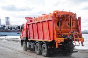 A red dump truck, painted in a bright shade of crimson, is currently parked conveniently on the side of the road, ready for its next task, whether it be for construction or transport needs photo